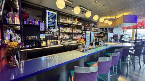 The Flipside backbar, full liquor wall under warm lighting